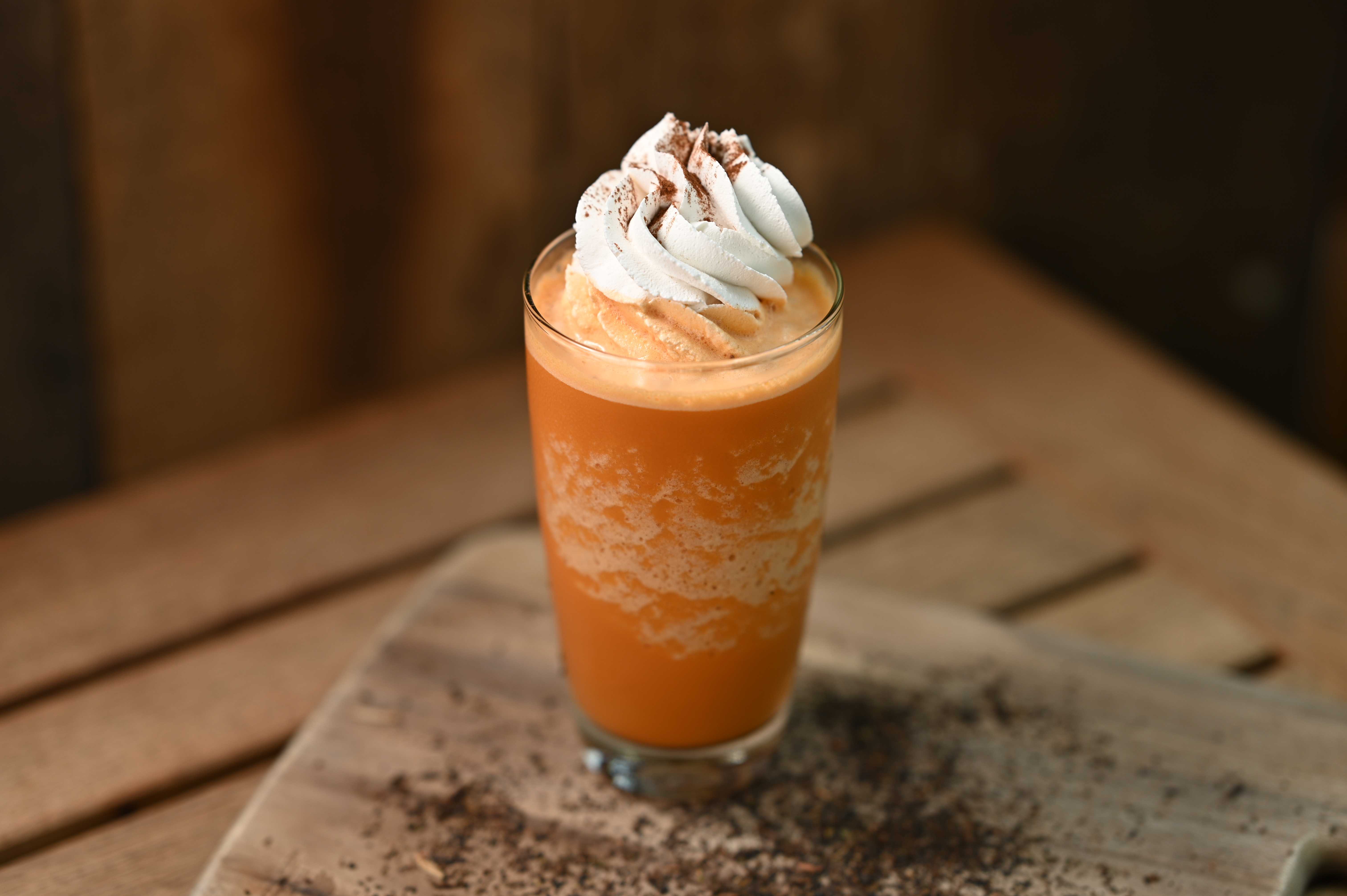 Smoothie Thai Tea Creamy: Gelas tinggi berisi smoothie Thai Tea berwarna jingga cerah