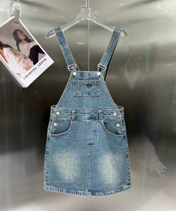 PRADA LOGO-PLAQUE DENIM BIB DRESS ชุดเดรส เอี๊ยมยีนส์ แบรนด์ปราด้า สามเหลี่ยมโลโก้โลหะสีเงิน